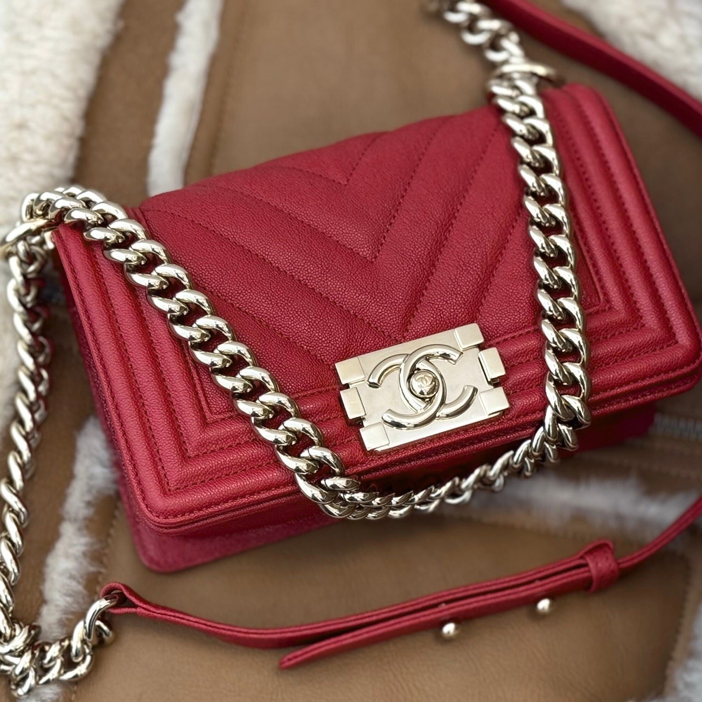 Red Chanel handbag with silver hardware on top of a shearling and brown jacket.