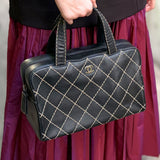 Black quilted handbag with top handles, gold lattice stitching, and CHANEL logo