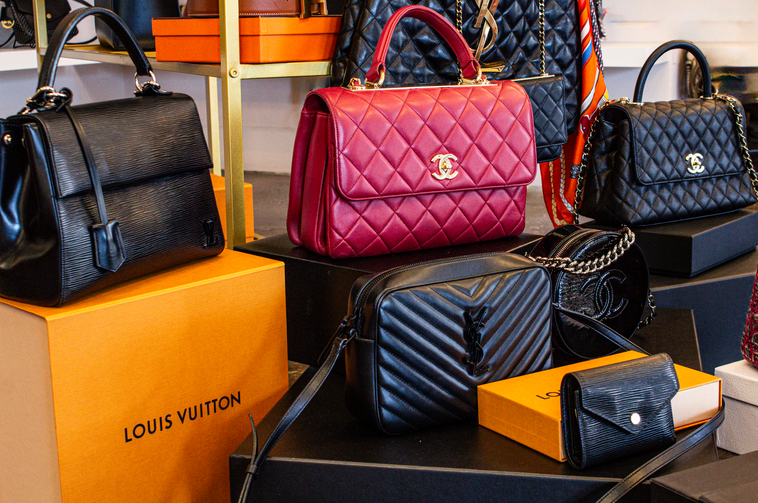 A collection of luxury handbags, mostly black and red, arranged in a display.