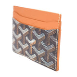 Men’s card case wallet, angled view with orange lining and dark monogram pattern