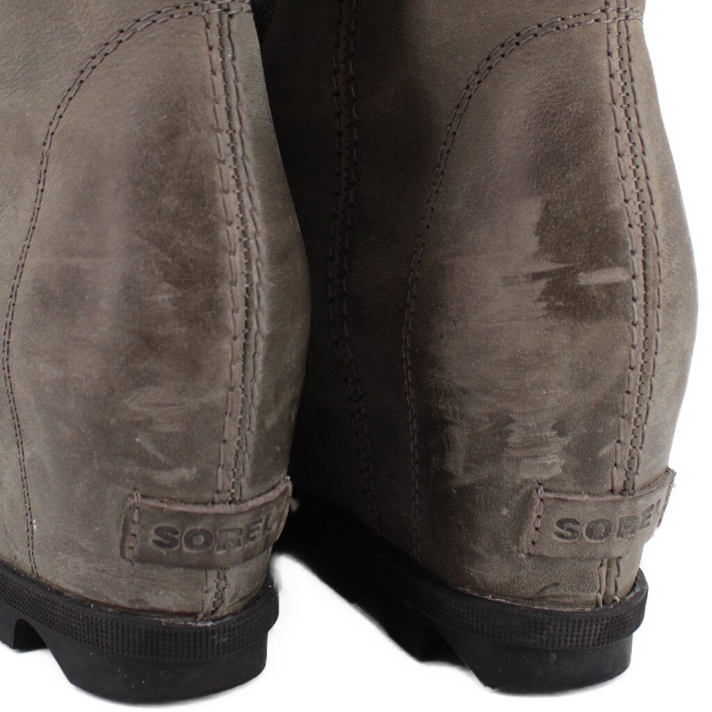 Gray suede wedge ankle boots heel close-up with embroidered brand mark
