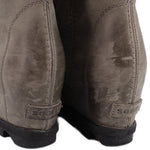 Gray suede wedge ankle boots heel close-up with embroidered brand mark