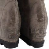 Gray suede wedge ankle boots heel close-up with embroidered brand mark