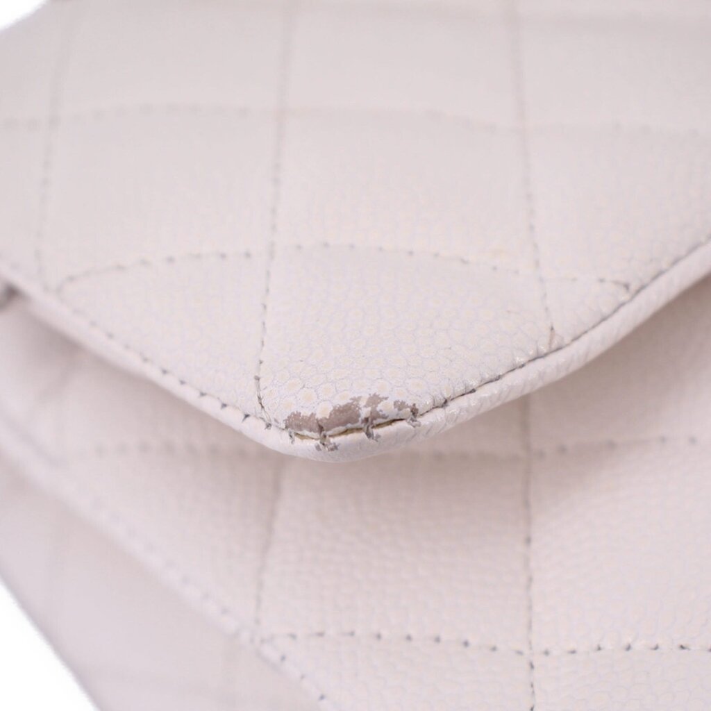 Close-up of off-white quilted CHANEL bag corner showing worn stitching
