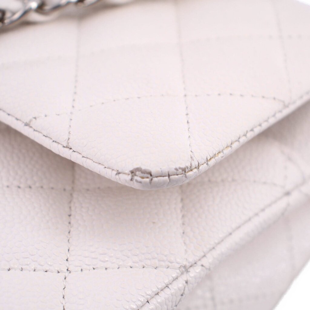 Close-up of off-white quilted CHANEL bag edge with chain hardware