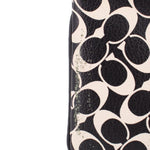 Logo canvas wristlet pouch close-up, textured black and cream pattern, stitched edge