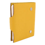 Yellow textured notebook cover partially open with white pages and snap hardware