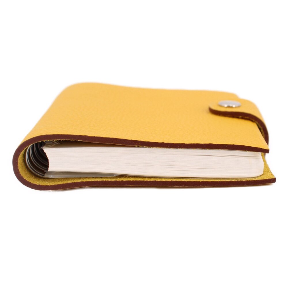 Yellow notebook with white page block, brown edge trim, and small top snap tab