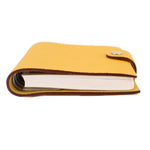 Yellow notebook with white page block, brown edge trim, and small top snap tab