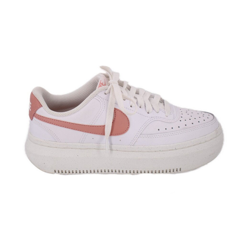 White Nike platform sneakers, lateral side view with pink swoosh and lace-up