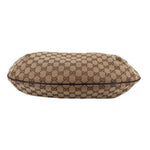 Brown GG canvas crossbody bag with top zipper across the rounded flapless opening