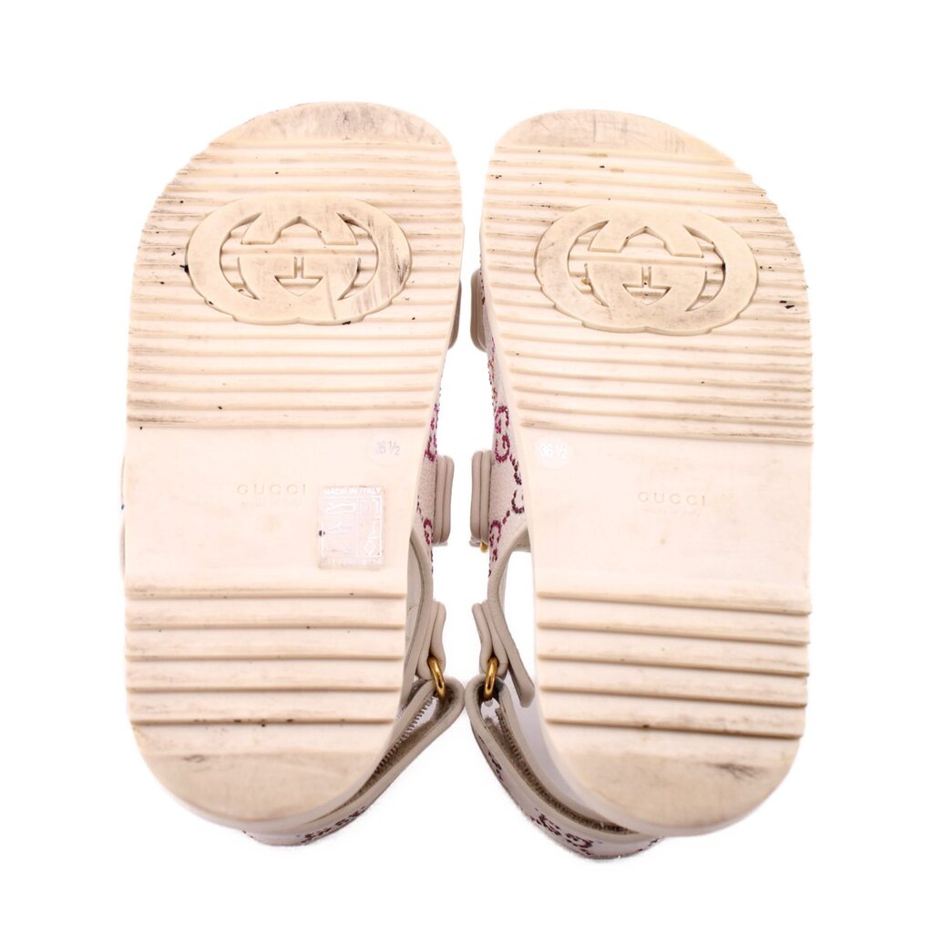 Cream rubber outsoles with tread and embossed logo, sandal pair bottom view