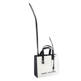 White mini tote with black panels and crossbody strap, brand text on front