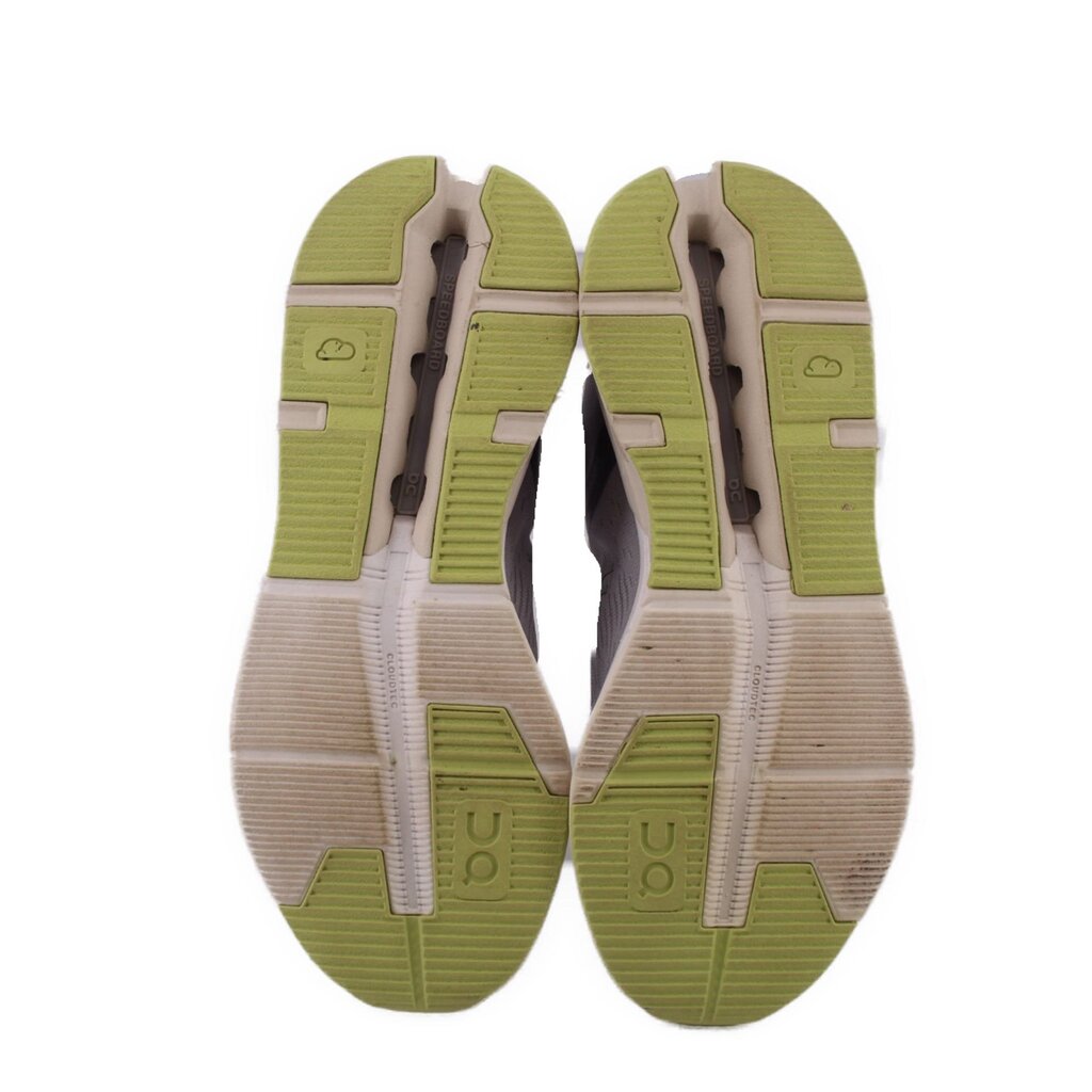 Shoe outsoles with green tread pods and light beige rubber, visible cushioning channels