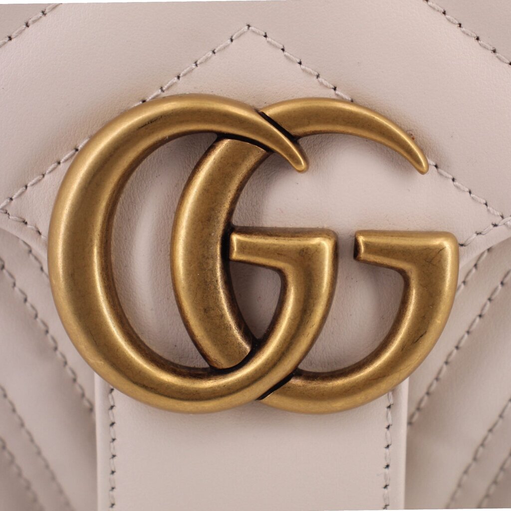 Gold-tone GG hardware on cream flap with surrounding stitch details