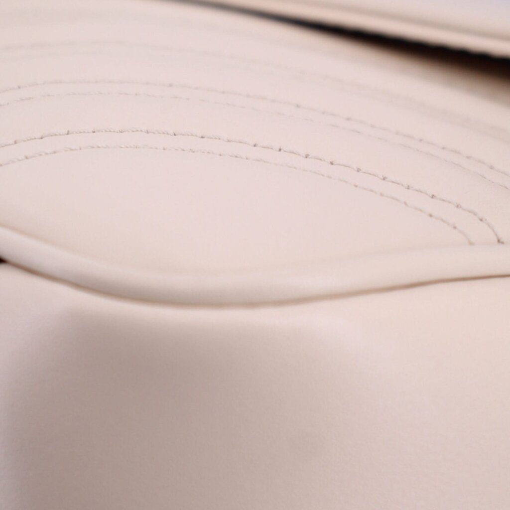 Cream leather close-up with visible stitching along curved seam