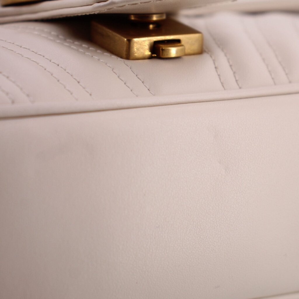 Cream flap shoulder bag with gold-tone clasp and quilted stitching