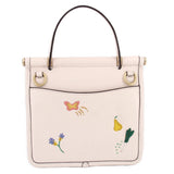 Cream top-handle bag with butterfly charm, garden embroidery, and gold top handles
