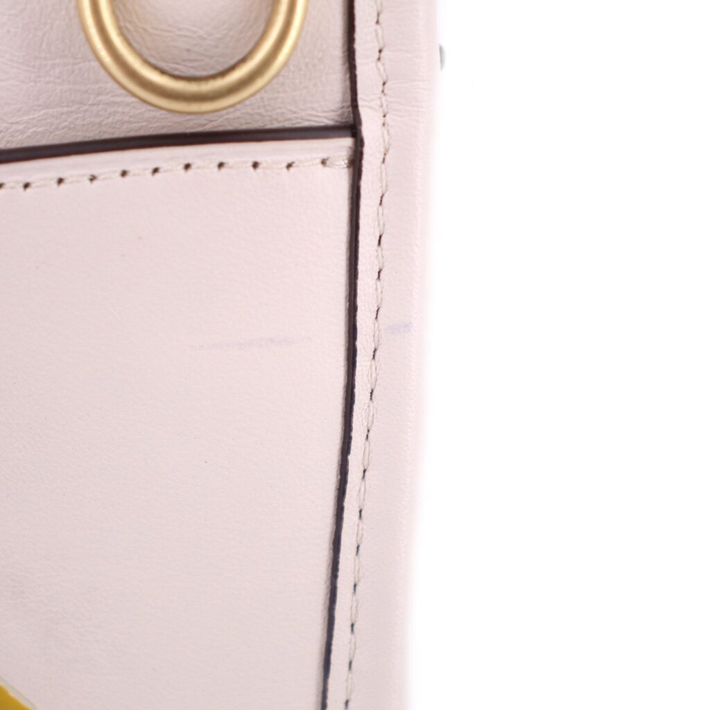Close-up of cream bag seam and gold D-ring hardware