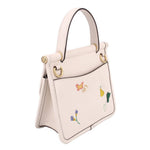Cream top-handle bag side view with embroidered flowers and gold hardware