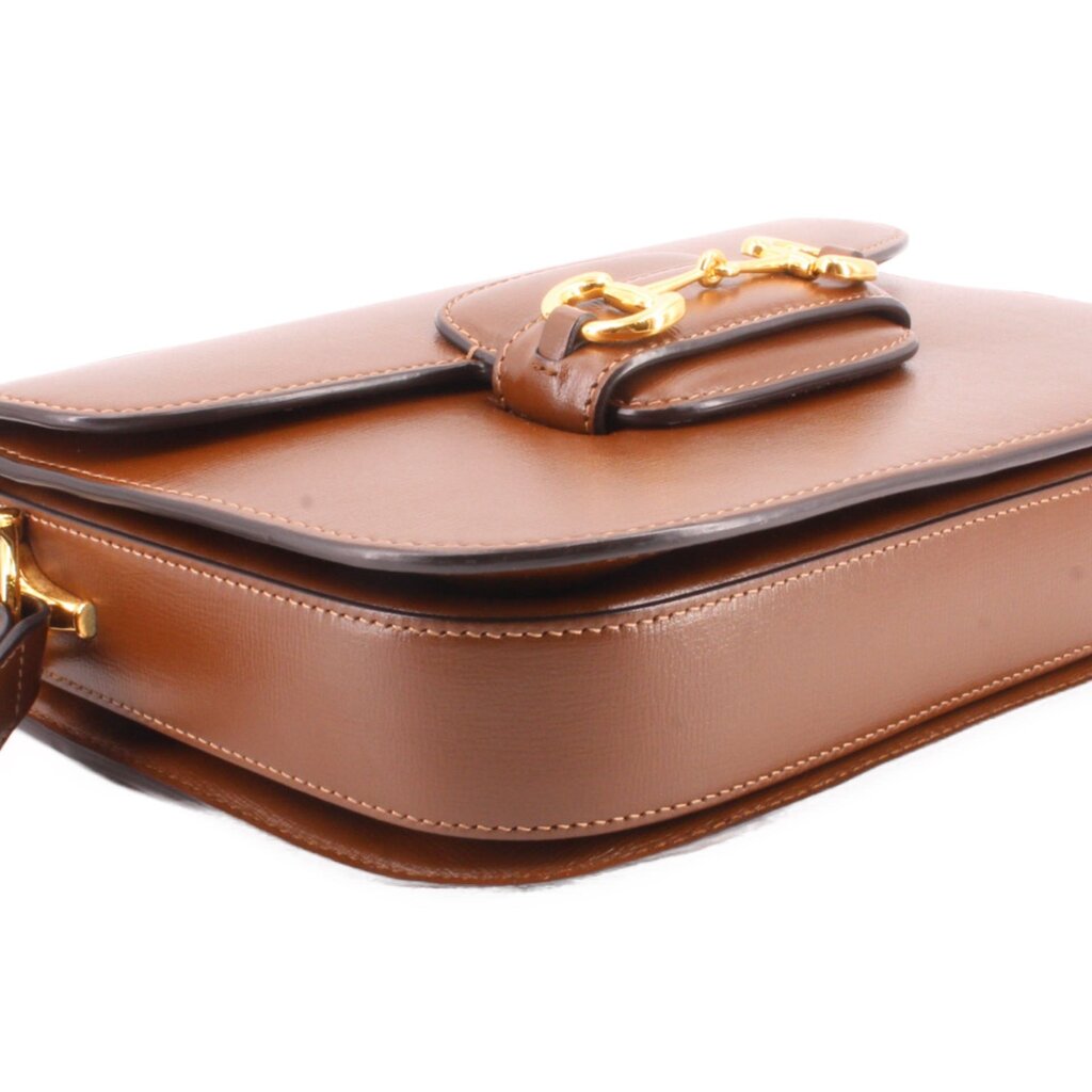 Brown leather shoulder bag close-up of top fold and Horsebit clasp.