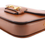 Brown leather shoulder bag corner close-up with Horsebit hardware and stitching.