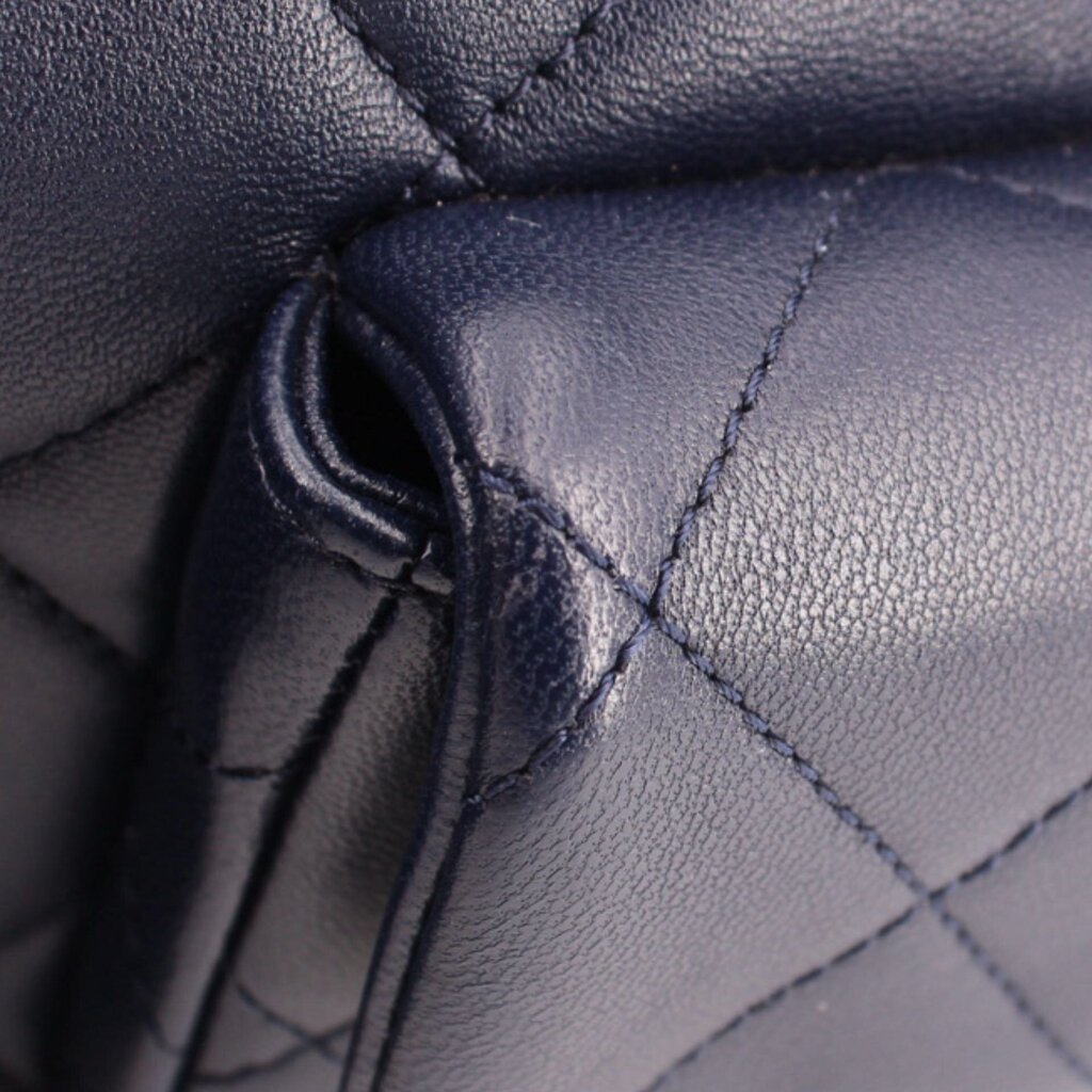 Navy quilted leather shoulder bag corner with pleated fold and visible seam stitching