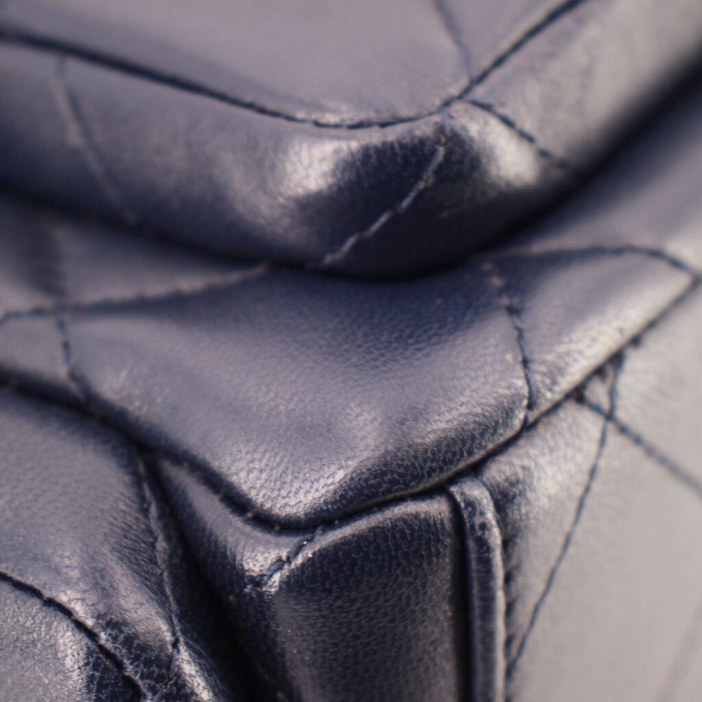 Dark navy leather close-up showing curved stitching and quilted panels