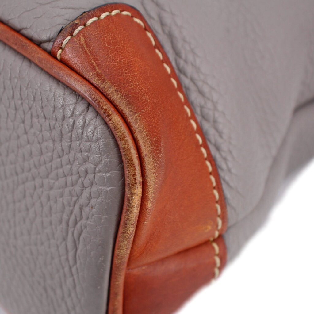 Taupe pebbled leather close-up with brown trim and contrast stitching along the edge