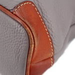 Taupe pebbled leather close-up with brown trim and contrast stitching along the edge