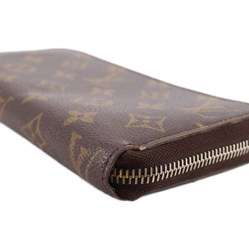 Monogram wallet corner close-up with textured brown leather and silver zipper teeth