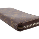 Monogram wallet corner close-up with textured brown leather and silver zipper teeth