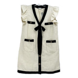 White and black button-up dress with ruffled sleeves, patch pockets, and black bow tie