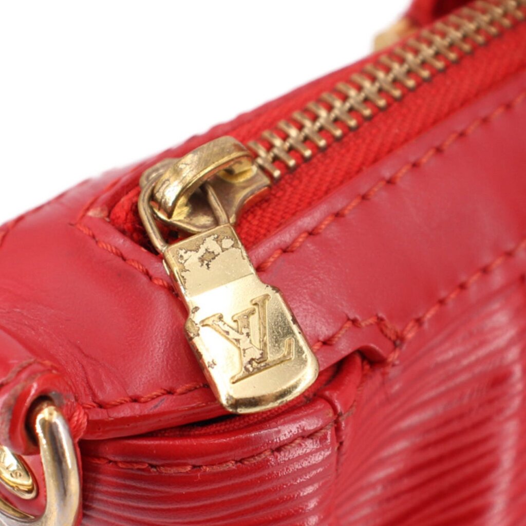 Close-up of gold-tone zipper pull and LV clasp on red LOUIS VUITTON bag
