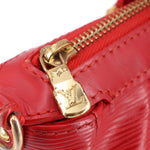 Close-up of gold-tone zipper pull and LV clasp on red LOUIS VUITTON bag