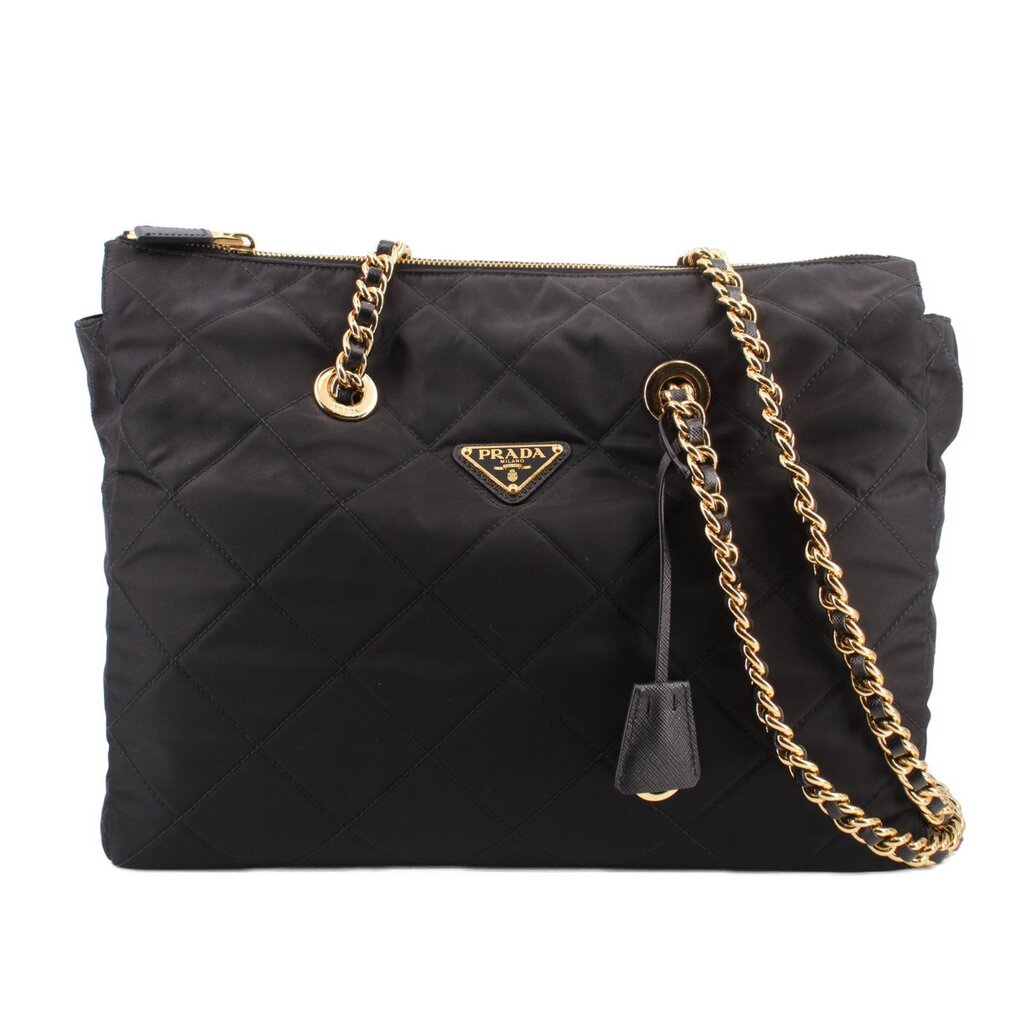 Black quilted tote bag with gold chain strap, top zip, and Prada logo plaque