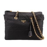 Black quilted tote bag with gold chain strap, top zip, and Prada logo plaque