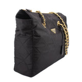 Black quilted tote bag with gold chain strap and Prada logo triangle, side profile