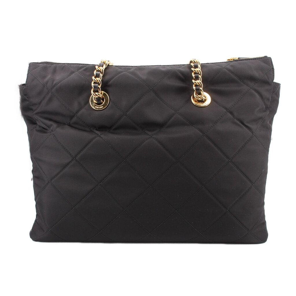 Black quilted tote bag with gold chain handles and zip top, back view