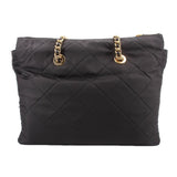 Black quilted tote bag with two gold chain top rings and top zip closure