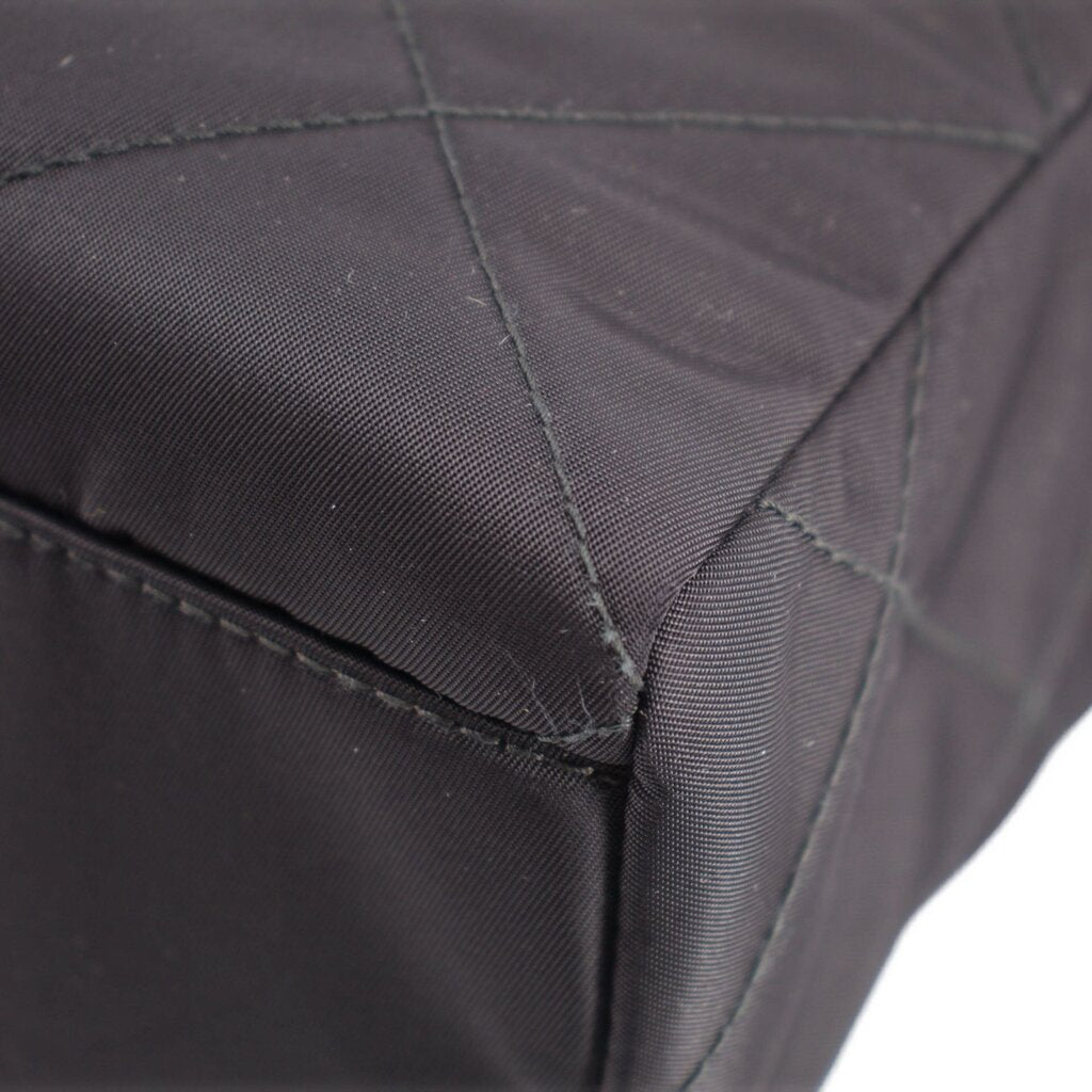 Black quilted tote bag corner with reinforced stitching and textured fabric edge