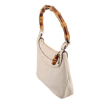 Cream bamboo shoulder bag angled side view with bamboo top handle and metal clasp