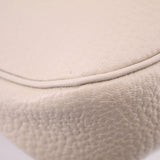 Cream pebbled leather bag edge close-up with smooth curved seam