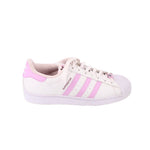 White low sneakers with pink side stripe accents, lace-up design, and SuperStar logo