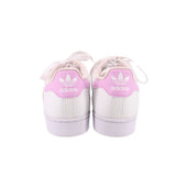 Back view of white sneakers with pink adidas logo on heel tabs