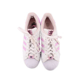 Pair of white lace-up sneakers with pink accents showing tongues and inner lining