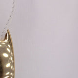 Close-up of white leather crossbody tote edge with metallic logo snap