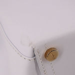 Close-up of white leather crossbody tote strap attachment with gold snap button