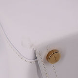 Close-up of white leather crossbody tote strap attachment with gold snap button
