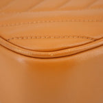 Orange leather panel seam close-up with curved stitching on Kira crossbody bag